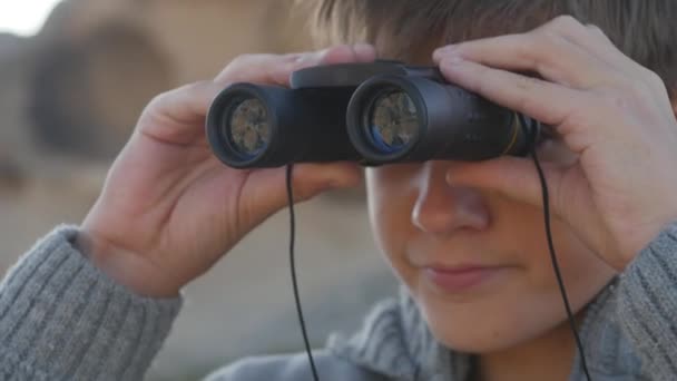 Schooljongen kijkt door een verrekijker — Stockvideo