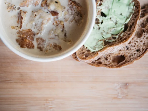 Creamy mushroom soup in cardboard cup served with bread with green color butter — Stock Photo, Image
