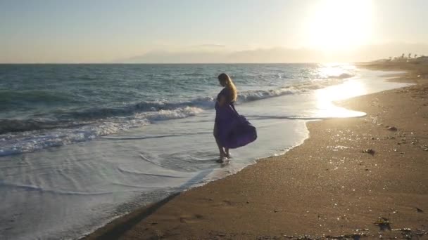 Jovem mulher de vestido andando sozinha junto ao mar — Vídeo de Stock