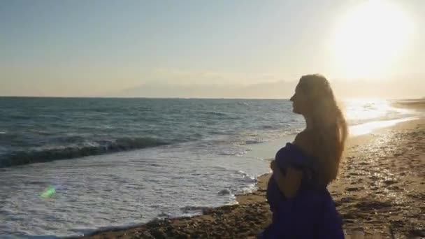 Nuori nainen mekko kävelee yksin meren rannalla — kuvapankkivideo