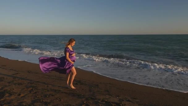 Молодая женщина в платье, идущая одна у моря — стоковое видео