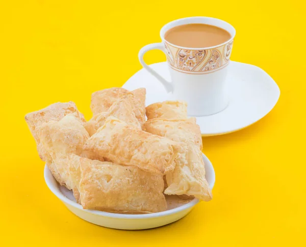 Indian Tea Time Breakfast Khari Also Know as Kharee, Khari Biscuit or Salty Puff Pastry Snacks, Served with Indian Hot Masala Chai or Hot Tea on Yellow Background