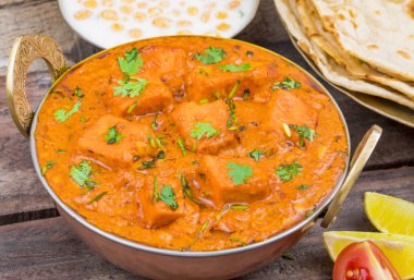 Hint Lezzetli Mutfağı Paneer Paneer Tikka Masala ve Tandoori Chapati ayrıca Paneer Butter Masala olarak da bilinir Tahta Arkaplanda Baharatlı Peynir ile servis edilen Hint Tabağı.