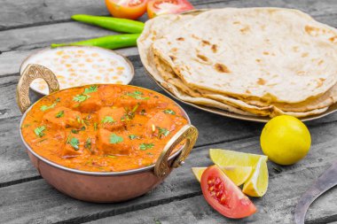Hint Lezzetli Mutfağı Paneer Paneer Tikka Masala ve Tandoori Chapati ayrıca Paneer Butter Masala olarak da bilinir Tahta Arkaplanda Baharatlı Peynir ile servis edilen Hint Tabağı.