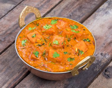 Hint Lezzetli Mutfağı Paneer Tikka Masala diğer adıyla Paneer Butter Masala ahşap arka planda baharatlı sosta servis edilen bir Hint Marinated Paneer Peynir Tabağı.
