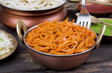 Baharatlı Kızarmış Sebze Chow Mein, Yeşil ve Kırmızı Chutney ile servis edilir ayrıca Erişte veya Hakka Eriştesi olarak da bilinir.