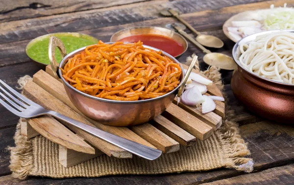 Baharatlı Kızarmış Sebze Chow Mein, Yeşil ve Kırmızı Chutney ile servis edilir ayrıca Erişte veya Hakka Eriştesi olarak da bilinir.