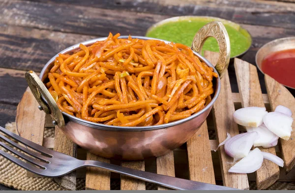 Baharatlı Kızarmış Sebze Chow Mein, Yeşil ve Kırmızı Chutney ile servis edilir ayrıca Erişte veya Hakka Eriştesi olarak da bilinir.