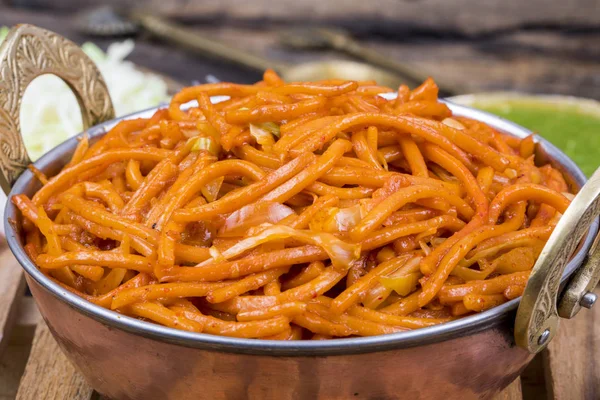 Baharatlı Kızarmış Sebze Chow Mein, Yeşil ve Kırmızı Chutney ile servis edilir ayrıca Erişte veya Hakka Eriştesi olarak da bilinir.