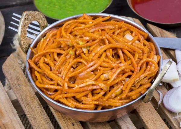 Baharatlı Kızarmış Sebze Chow Mein, Yeşil ve Kırmızı Chutney ile servis edilir ayrıca Erişte veya Hakka Eriştesi olarak da bilinir.