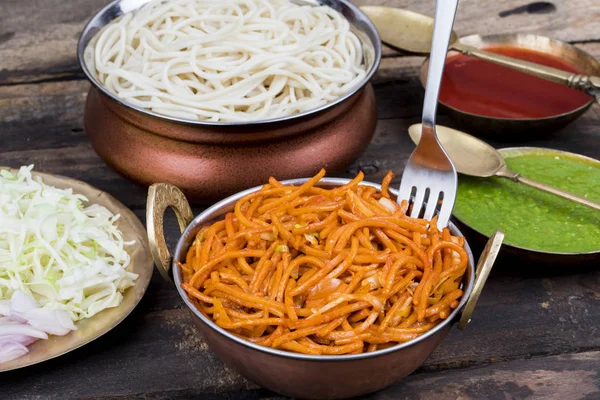 Baharatlı Kızarmış Sebze Chow Mein, Yeşil ve Kırmızı Chutney ile servis edilir ayrıca Erişte veya Hakka Eriştesi olarak da bilinir.