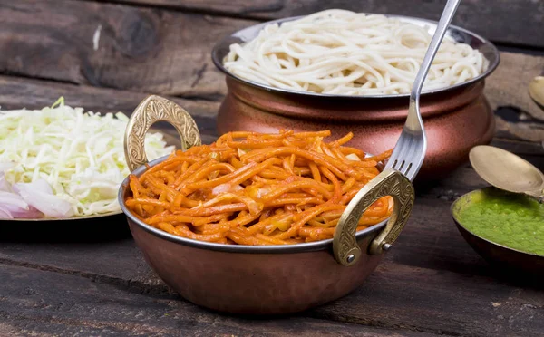 Baharatlı Kızarmış Sebze Chow Mein, Yeşil ve Kırmızı Chutney ile servis edilir ayrıca Erişte veya Hakka Eriştesi olarak da bilinir.