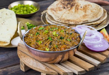 Hint mutfağı Sev Tamaeta ya da Sev Tameta da Chapati, Papad, Onion ya da Raita ile servis edilir. Domatesli ve soğan soslu, ahşap masa üzerinde baharatlı Sev soslu.