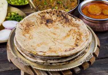 Hint Mutfağı Chapati, Roti, Flatbread, Chapathi veya Chapatti olarak da adlandırılır Sev Tamatar, Gatta Curry, Raita, Papad veya soğan ile birlikte ahşap arka planda servis edilir