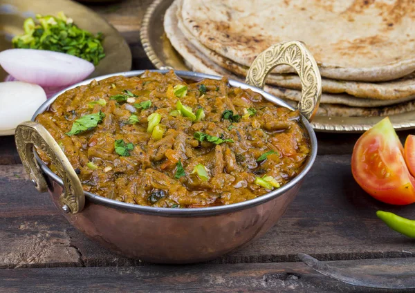 印度菜Sev Tamatar又名Sev Tamaeta或Sev Tameta 与Chapati Papad Onion或Raita一起食用 它是用番茄和洋葱肉汁在木桌上做的 还有一把调味的塞子 — 图库照片