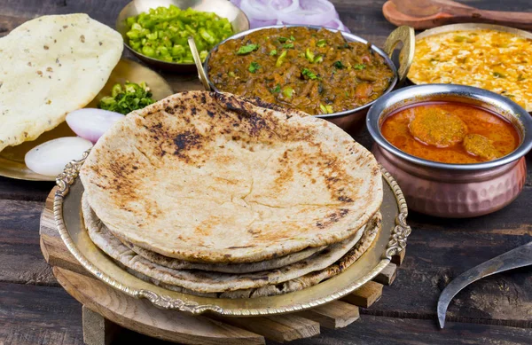 Hint Mutfağı Chapati, Roti, Flatbread, Chapathi veya Chapatti olarak da adlandırılır Sev Tamatar, Gatta Curry, Raita, Papad veya soğan ile birlikte ahşap arka planda servis edilir