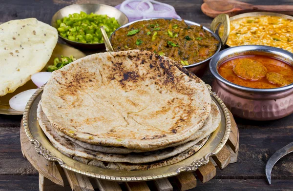 Hint Mutfağı Chapati, Roti, Flatbread, Chapathi veya Chapatti olarak da adlandırılır Sev Tamatar, Gatta Curry, Raita, Papad veya soğan ile birlikte ahşap arka planda servis edilir