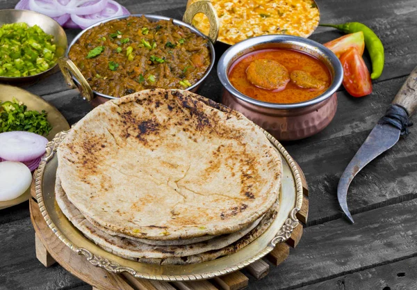 Hint Mutfağı Chapati, Roti, Flatbread, Chapathi veya Chapatti olarak da adlandırılır Sev Tamatar, Gatta Curry, Raita, Papad veya soğan ile birlikte ahşap arka planda servis edilir