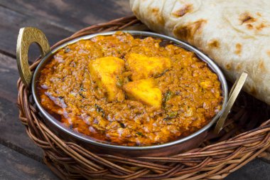 Hint mutfağı Kadai Paneer Tandoori ile servis edilir ayrıca Kadhai Paneer ya da Karahi Paneer olarak da bilinir eski ahşap arka planda baharatlı bir sos ile servis edilen marinated Paneer Cheese Dish Hint yemeğidir.