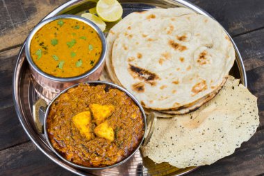 Hint Geleneksel Thali Food Dal Makhani Chapati, Papad, Kadai Paneer veya Lemon Also Know ile birlikte Dal Makhni veya Daal Makhani olarak hizmet vermektedir. Eski Ahşap Arkaplanda