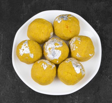 Besan Laddu Hint geleneksel tatlı yiyecek de biliyorum Laddoos, laddoo, gidecektir, laddo Are Ball-Shaped tatlılar popüler Hint Festivaller gibi. Laddu siyah dokulu arka plan üzerinde