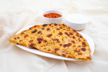 Hint Geleneksel Kahvaltı Tabağı Aloo Paratha taze krema ve turşuyla servis edilen bir patates dolgulu ekmek.