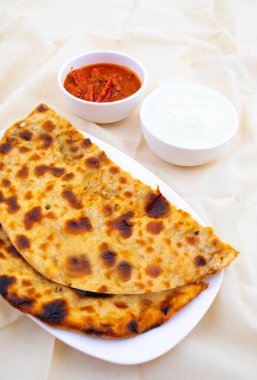 Hint Geleneksel Kahvaltı Tabağı Aloo Paratha taze krema ve turşuyla servis edilen bir patates dolgulu ekmek.