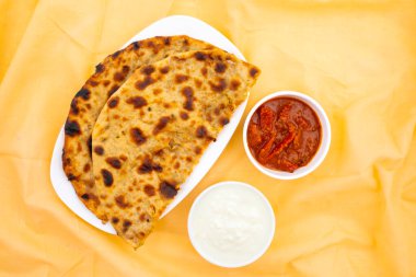 Hint Geleneksel Kahvaltı Tabağı Aloo Paratha taze krema ve turşuyla servis edilen bir patates dolgulu ekmek.