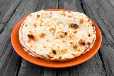 Indian Cuisine - Tandoori Roti whole wheat flat bread made from stoneground wholemeal flour, Traditionally known as atta, and water that is combined into a dough clipart