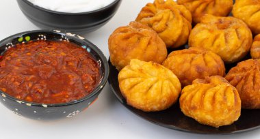 Kızarmış Momos, Nepal 'den geleneksel bir hamur yemeğidir. Schezwan Sosu ve Krema ile servis edilir.