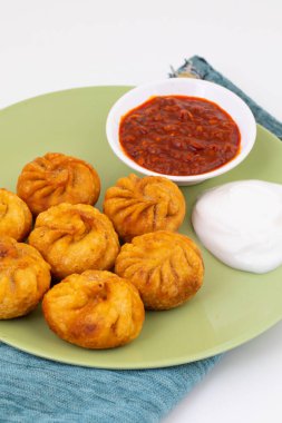 Kızarmış Momos, Nepal 'den geleneksel bir hamur yemeğidir. Schezwan Sosu ve Krema ile servis edilir.