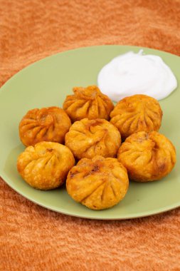 Kızarmış Momos, Nepal 'den geleneksel bir hamur yemeğidir. Schezwan Sosu ve Krema ile servis edilir.