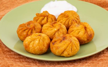 Kızarmış Momos, Nepal 'den geleneksel bir hamur yemeğidir. Schezwan Sosu ve Krema ile servis edilir.