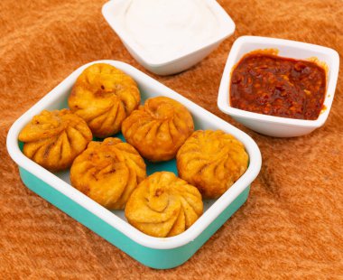 Kızarmış Momos, Nepal 'den geleneksel bir hamur yemeğidir. Schezwan Sosu ve Krema ile servis edilir.