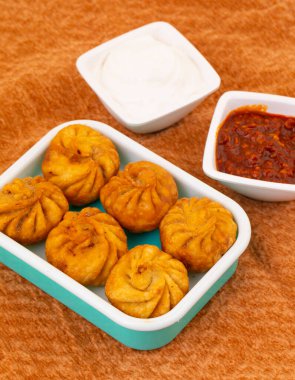 Kızarmış Momos, Nepal 'den geleneksel bir hamur yemeğidir. Schezwan Sosu ve Krema ile servis edilir.