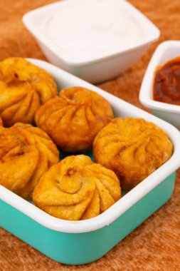 Kızarmış Momos, Nepal 'den geleneksel bir hamur yemeğidir. Schezwan Sosu ve Krema ile servis edilir.