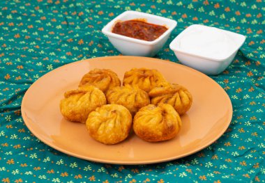 Kızarmış Momos, Nepal 'den geleneksel bir hamur yemeğidir. Schezwan Sosu ve Krema ile servis edilir.