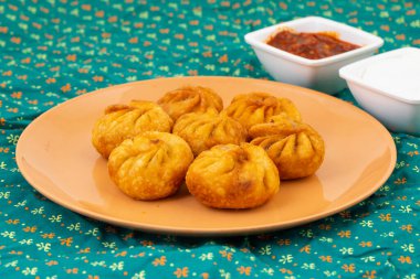 Kızarmış Momos, Nepal 'den geleneksel bir hamur yemeğidir. Schezwan Sosu ve Krema ile servis edilir.