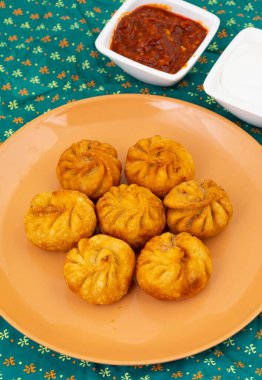 Kızarmış Momos, Nepal 'den geleneksel bir hamur yemeğidir. Schezwan Sosu ve Krema ile servis edilir.