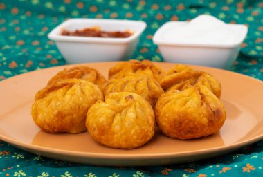Kızarmış Momos, Nepal 'den geleneksel bir hamur yemeğidir. Schezwan Sosu ve Krema ile servis edilir.