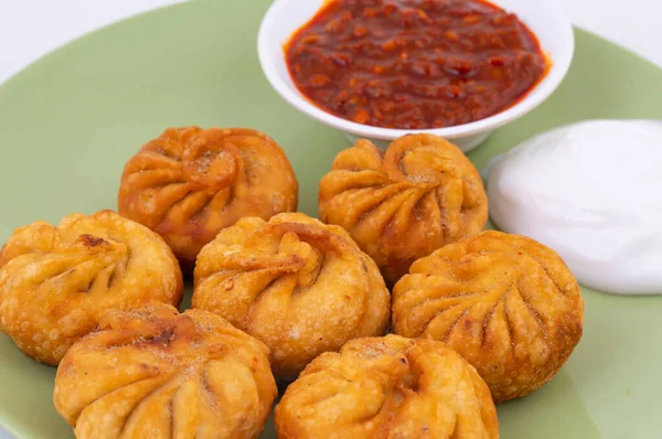 Kızarmış Momos, Nepal 'den geleneksel bir hamur yemeğidir. Schezwan Sosu ve Krema ile servis edilir.