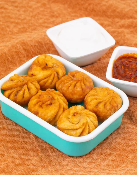 Kızarmış Momos, Nepal 'den geleneksel bir hamur yemeğidir. Schezwan Sosu ve Krema ile servis edilir.