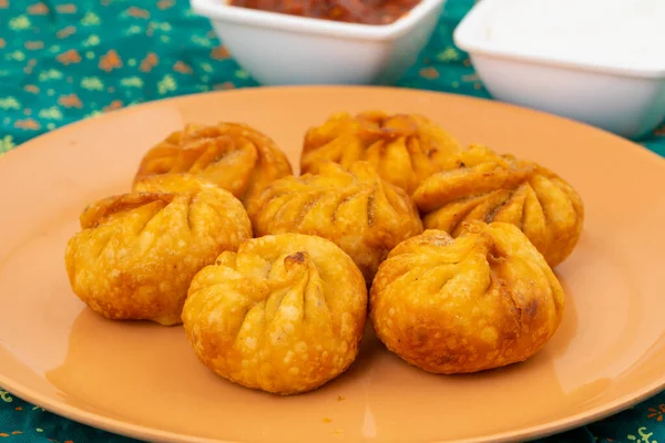 Kızarmış Momos, Nepal 'den geleneksel bir hamur yemeğidir. Schezwan Sosu ve Krema ile servis edilir.