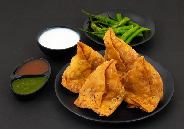 Hint Sokak Yemeği Samosa ya da Samosas, Maida & Doldurulmuş Patates, Bezelye ve Baharatların Çıtır Çıtır Çıtır Çıtır ve Baharatlı Üçgen Şekerlemesidir. Chutney, Ketçap veya Curd ile servis edilir.