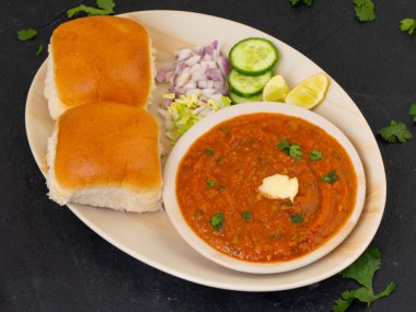 Pav Bhaji bir Hint Geleneksel Popüler Sokak Fast Food 'udur. Kalın ve baharatlı baharatlı köri yanında yumuşak ekmek rulosu ve tereyağlı çörek.