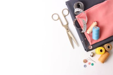 Dikiş aksesuarları ve kumaş üzerine beyaz bir arka plan. Dikiş ipliği, iğneleri, iğne, kumaş, düğmeler ve dikiş santimetre. Üstten Görünüm, flatlay 