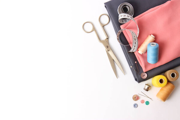 Sewing accessories and fabric on a white background. Sewing threads, needles, pins, fabric, buttons and sewing centimeter. top view, flatlay 