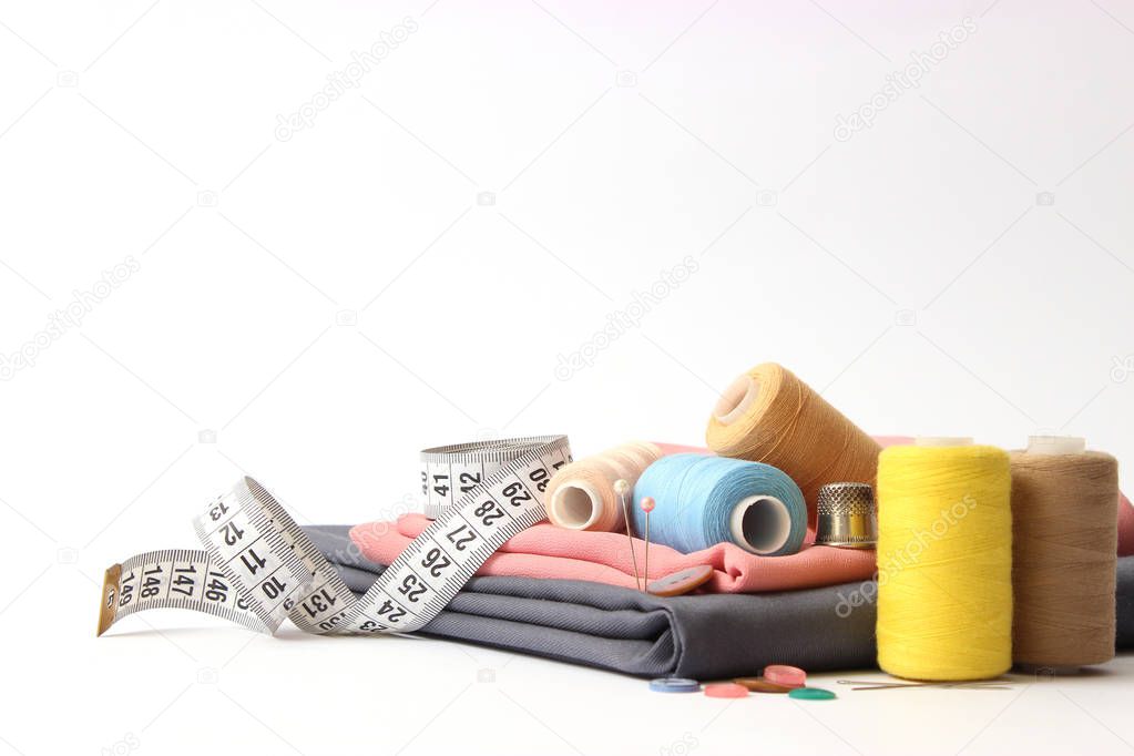 Sewing accessories and fabric on a white background. Sewing threads, needles, pins, fabric, buttons and sewing centimeter. top 