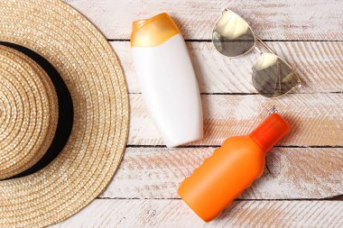 Güneş kremi, havlu, şapka, gözlük ahşap arka plan üzerinde. minimalizm, üstten görünüm, flatlay 