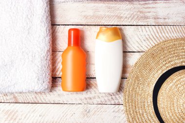 Güneş kremi, havlu, şapka, gözlük ahşap arka plan üzerinde. minimalizm, üstten görünüm, flatlay 
